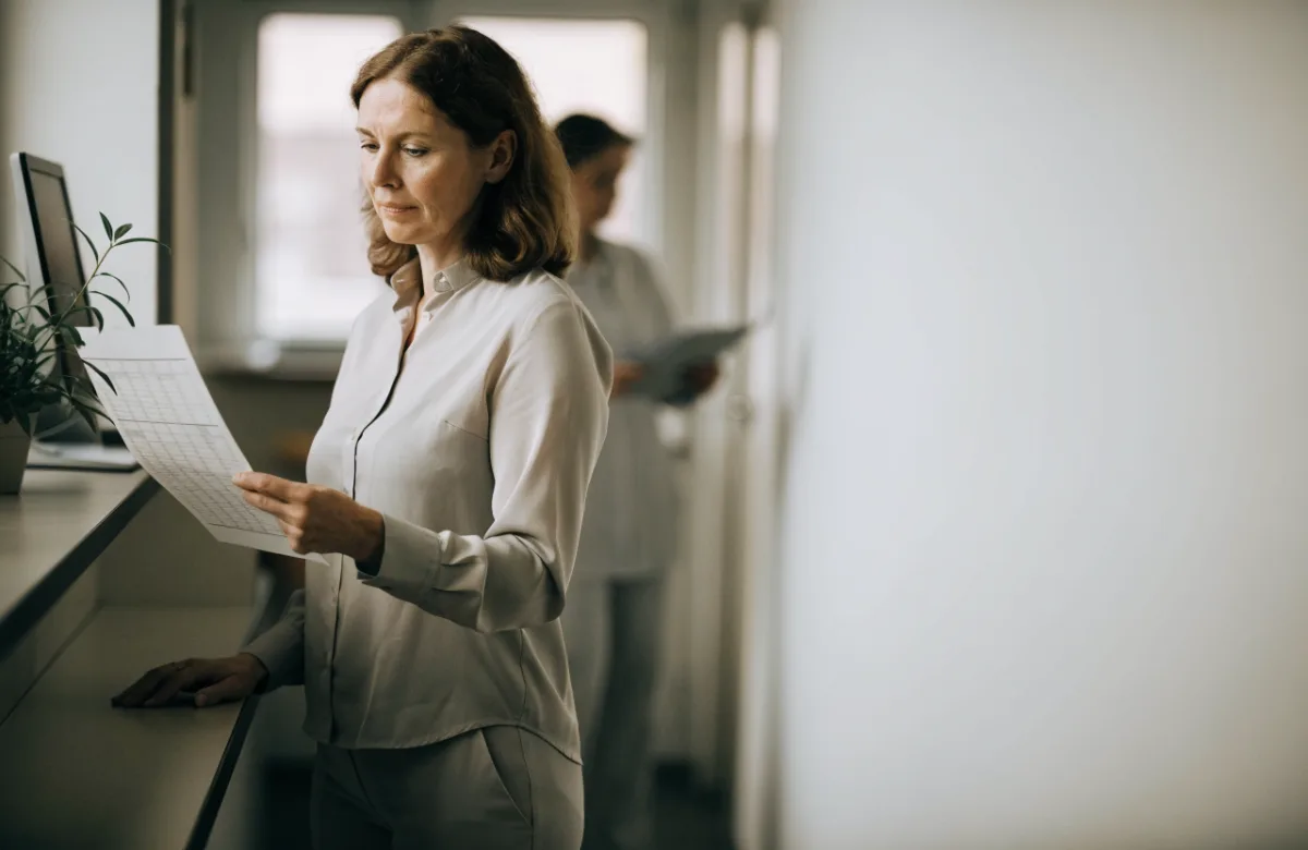 A practice manager reviewing the appointment schedule at a daylit clinic reception.